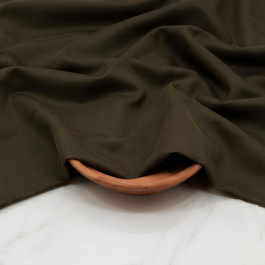 Brown fabric draped over a wooden bowl on a white surface