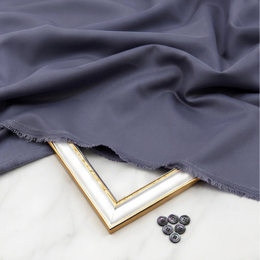 Dark gray fabric draped over a white surface with a gold frame and buttons.